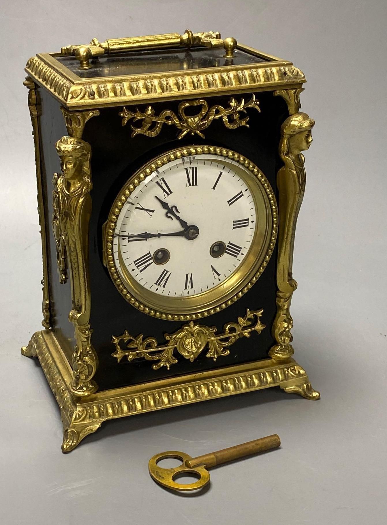 A French ebonised mantel clock with cast brass mounts, 9cm convex enamel dial, bell striking movement, height 27cm incl. handle